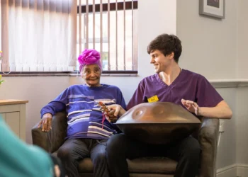 elderly woman and caregiver playing handpan drum together, both smiling and engaged